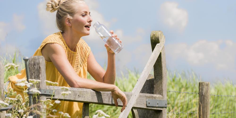 vrouw drinkt water bij hek